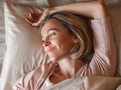 Woman resting in bed with dental implants