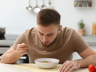 Man eating a bowl of soup in the kitchen