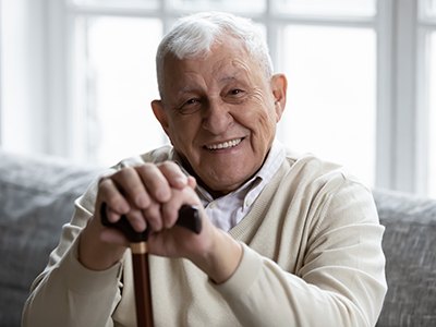 Senior man with cane sitting and smiling on couch