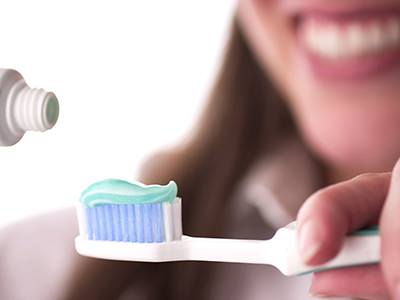 Lady places toothpaste on toothbrush